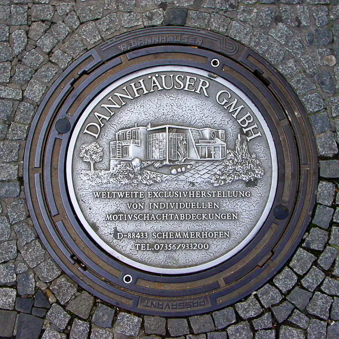 Dannhäuser GmbH ad on manhole cover in Gießen, Germany. Photo by Yuri Matrosovich